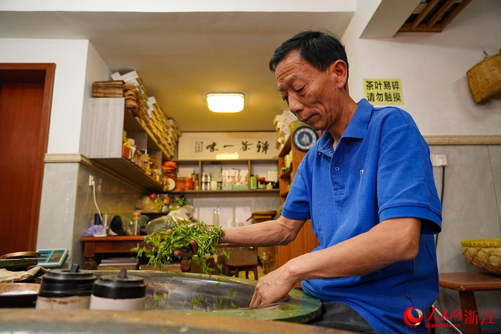 在杭州市西湖区转塘街道桐坞村，国家级非物质文化遗产代表性项目“西湖龙井采摘和制作技艺”传承人樊生华在炒制茶叶。人民网 章勇涛摄